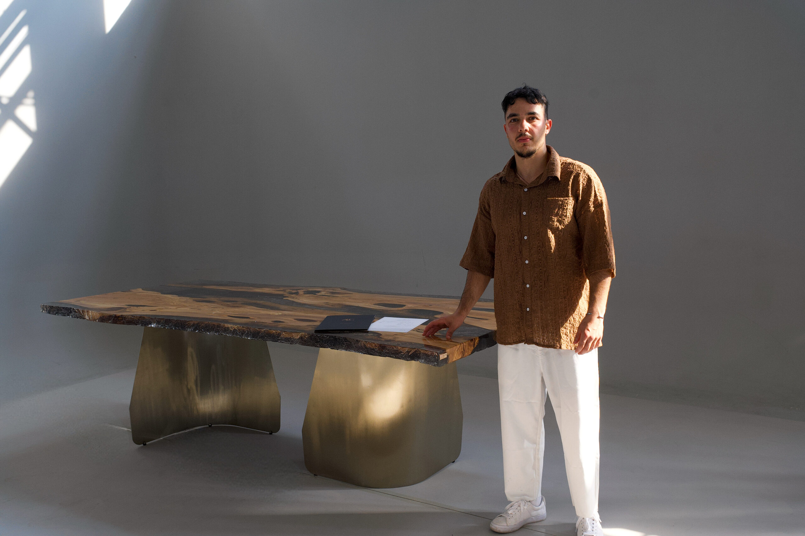Image of a person standing beside the Crystal Black Olive Dining Table in a well-lit space.