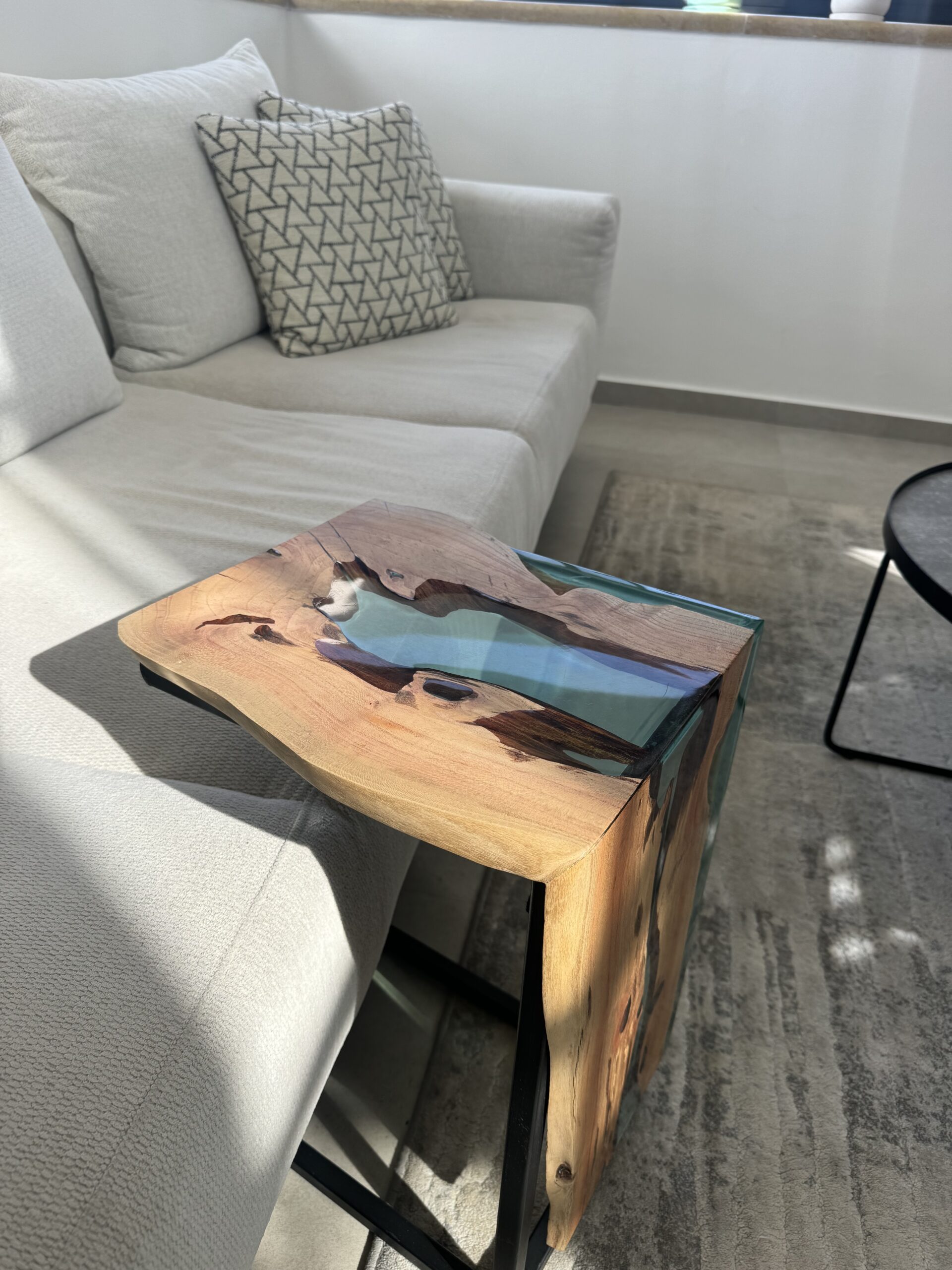 Another angle of the carob wood side table showing its unique design and epoxy finish.